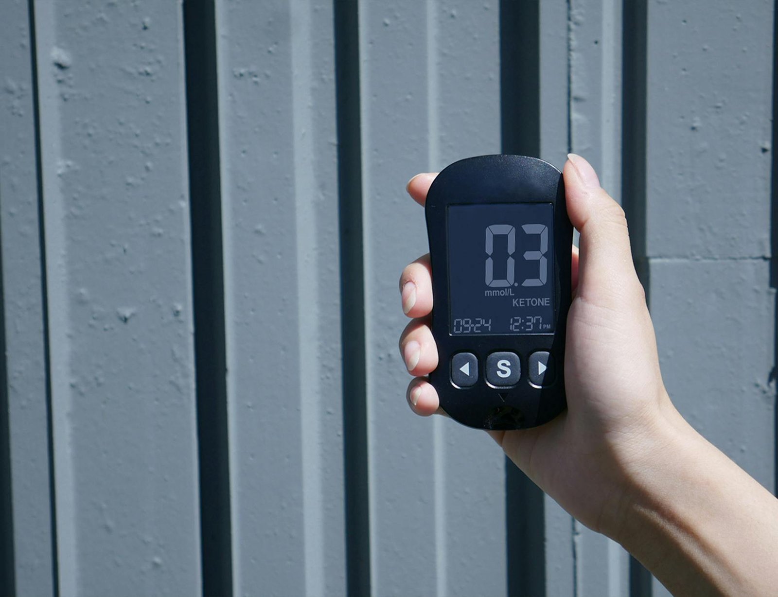 a person holding a digital thermometer in front of a wall